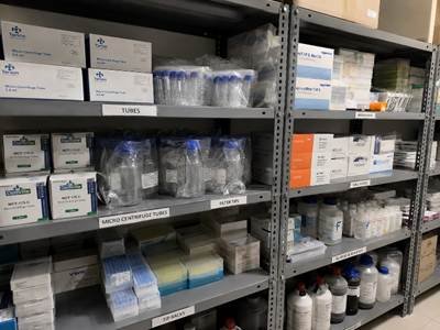 Lab storeroom shelf in a Bangalore research institution showing organised laboratory consumables — labelled boxes of tubes, tip racks, and reagent bottles