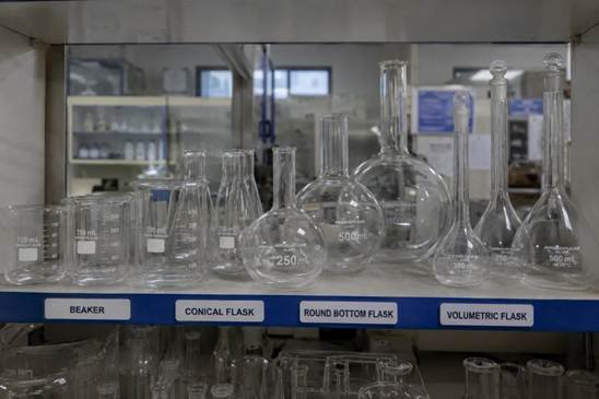 Borosilicate laboratory glassware — beakers, Erlenmeyer flasks and graduated cylinders — neatly arranged on a clean Bangalore research lab bench