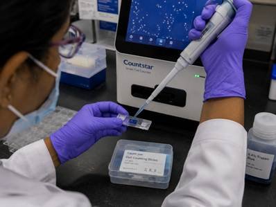 Researcher loading a cell counting slide into an automated cell counter in a Karnataka cell culture facility