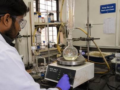 Researcher heating a borosilicate glass flask on a hotplate in a Karnataka research lab without cracking