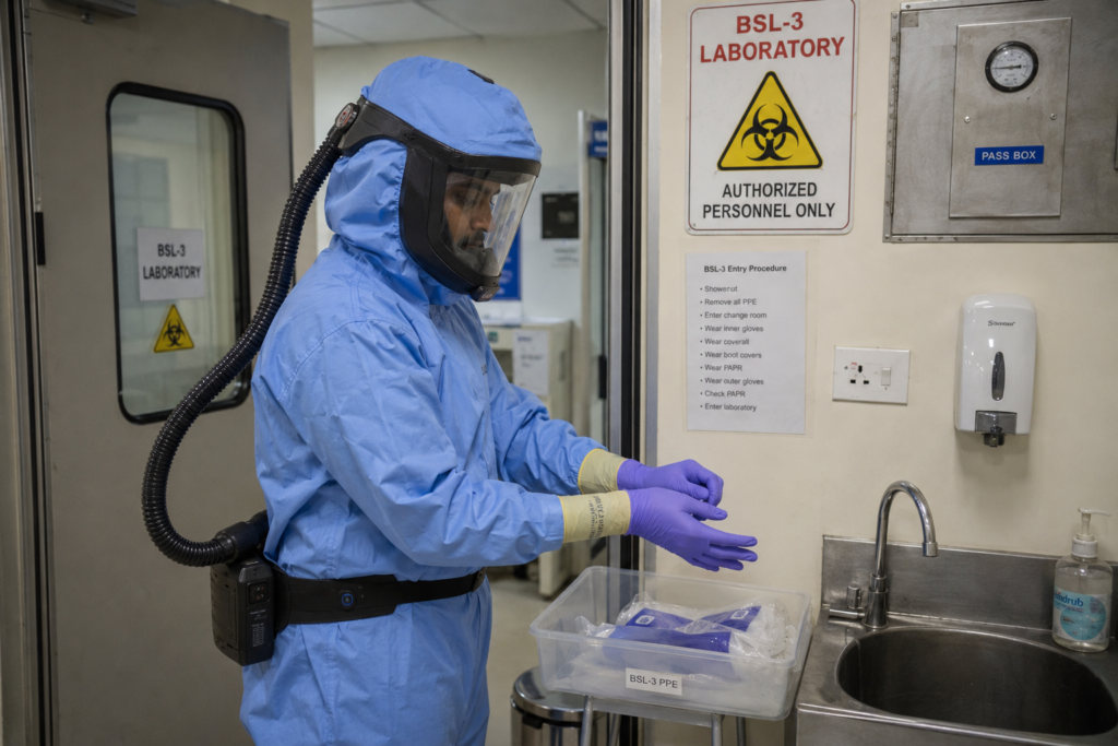 Researcher in BSL-3 appropriate PPE entering a Karnataka research institute high-containment lab