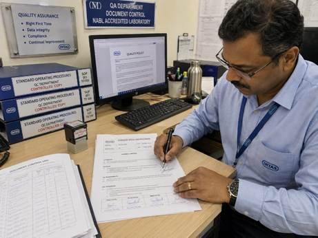 Lab manager reviewing and signing a new standard operating procedure document at a Karnataka pharmaceutical company quality department